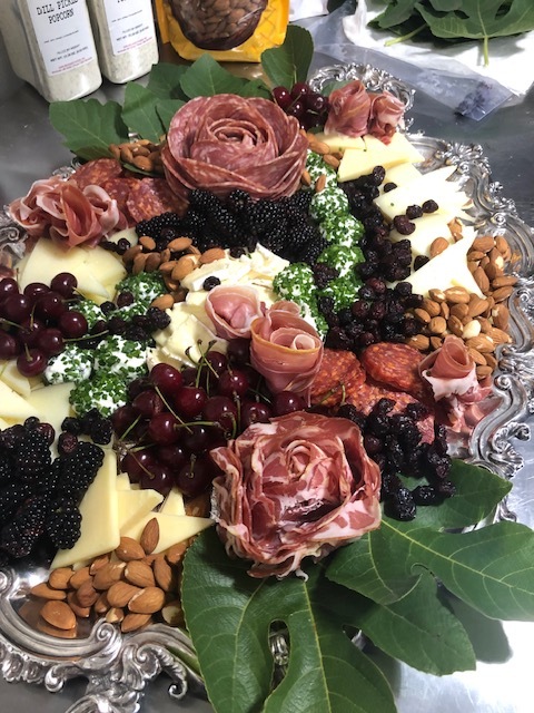 A charcuterie platter with salami roses, cheeses, cherries, blackberries, and almonds