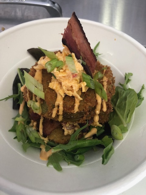 Fried green tomatoes stacked with pimento cheese, bacon, and green onion over mixed greens