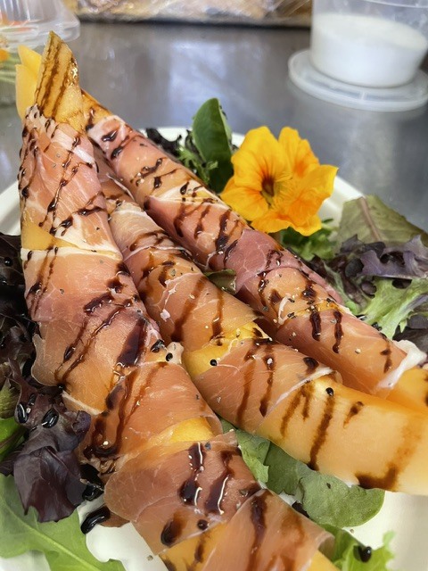 Prosciutto-wrapped melon with a balsamic drizzle and an edible flower