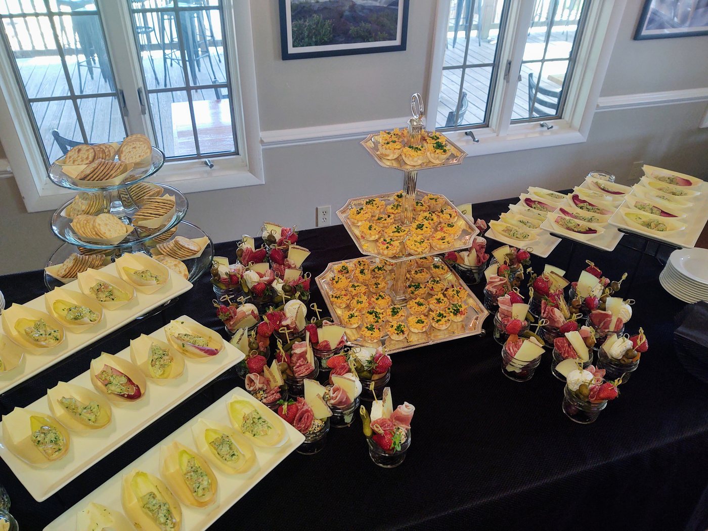 A catered appetizer spread with tartlets, charcuterie cups, and crackers