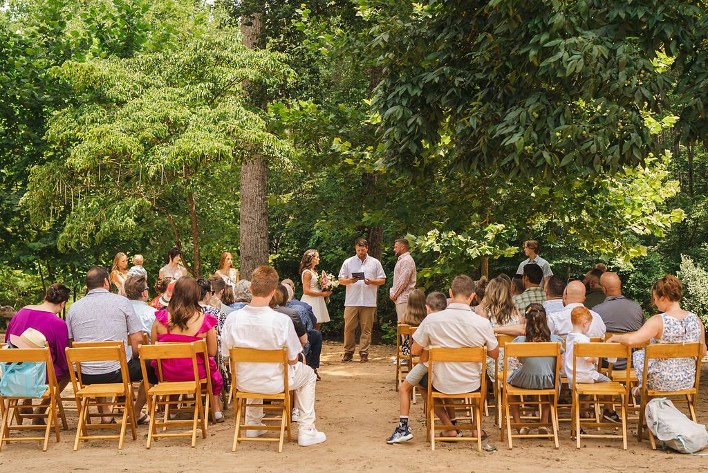A wedding ceremony in the woods with seated guests