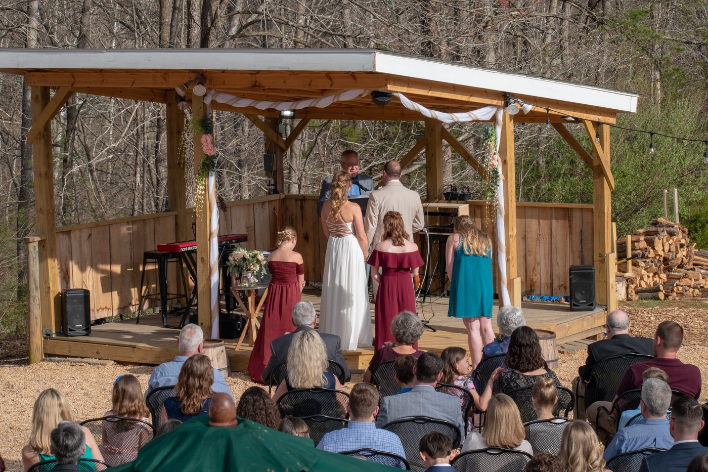 A couple exchange vows on the open-air pavilion, bridesmaids beside them
