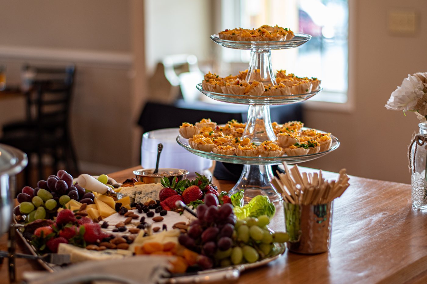 A tiered appetizer stand beside a large charcuterie board