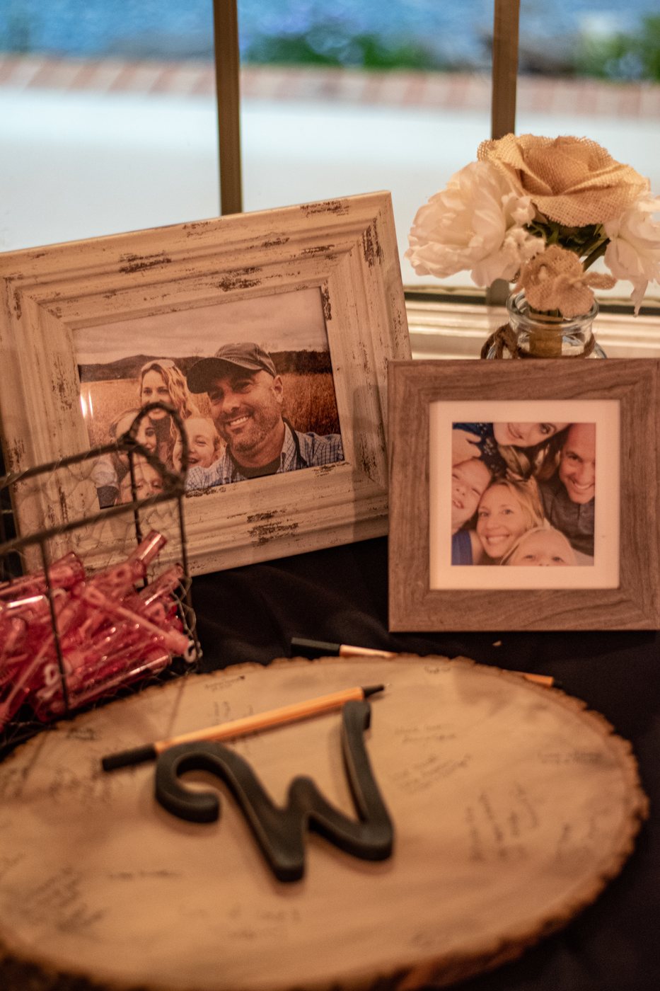 A rustic wedding guest-book table with framed photos and flowers